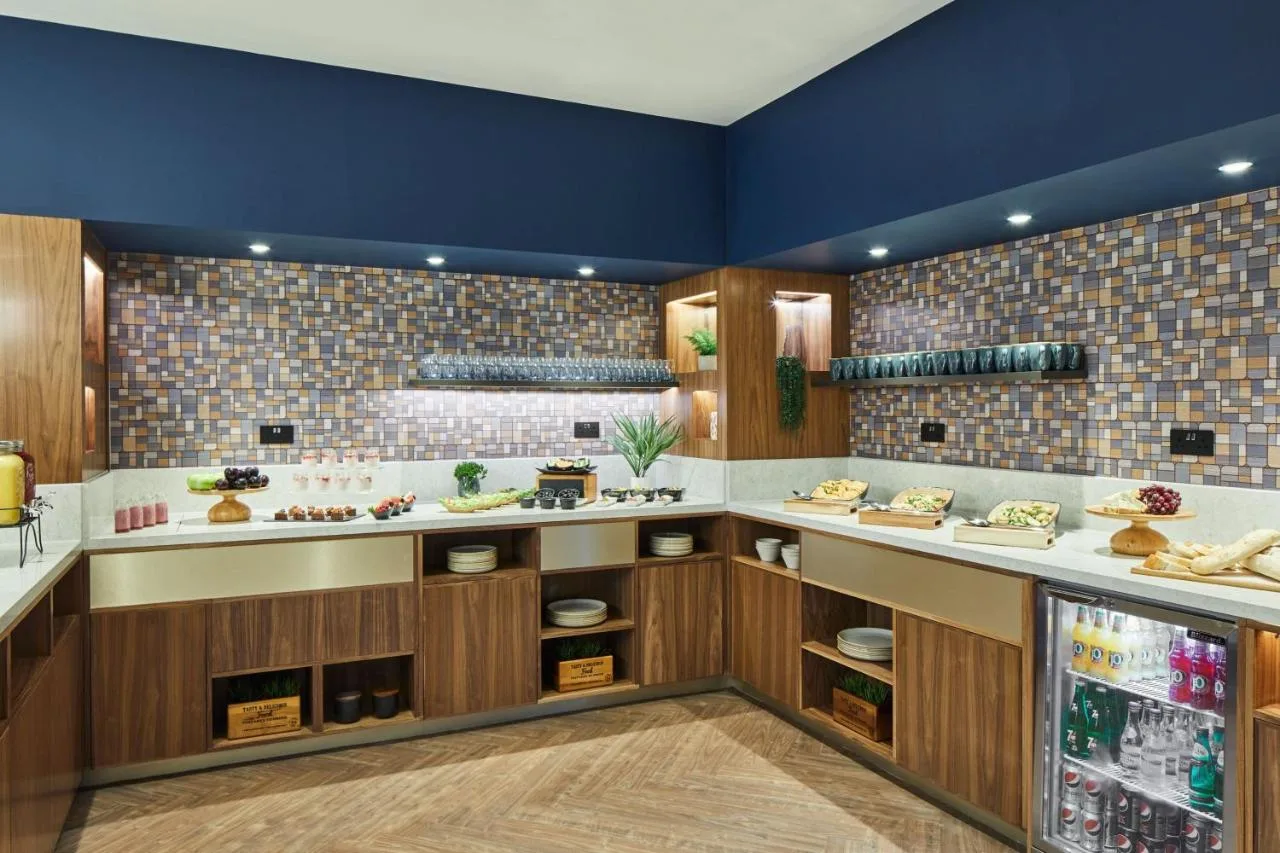 A kitchen with wooden cabinets and a blue wall at Cardiff Marriott Hotel in Cardiff